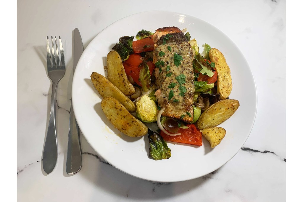 A fish dish on a white plate with potatoes and Brussels sprouts