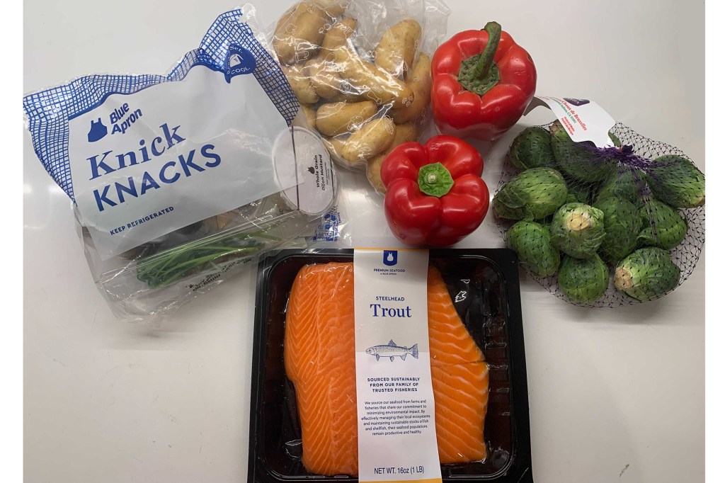 Trout, red peppers, potatoes, cabbage and a bag called "Knick Knacks" on a white counter